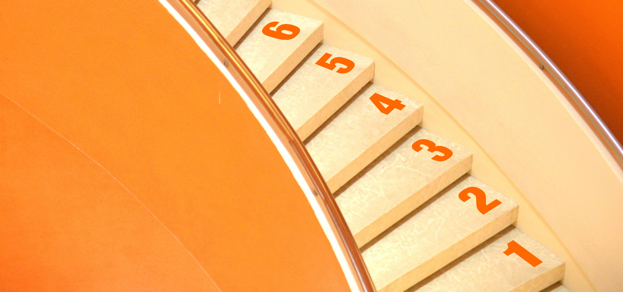 Photo of he steps in a spral staircase with orange walls